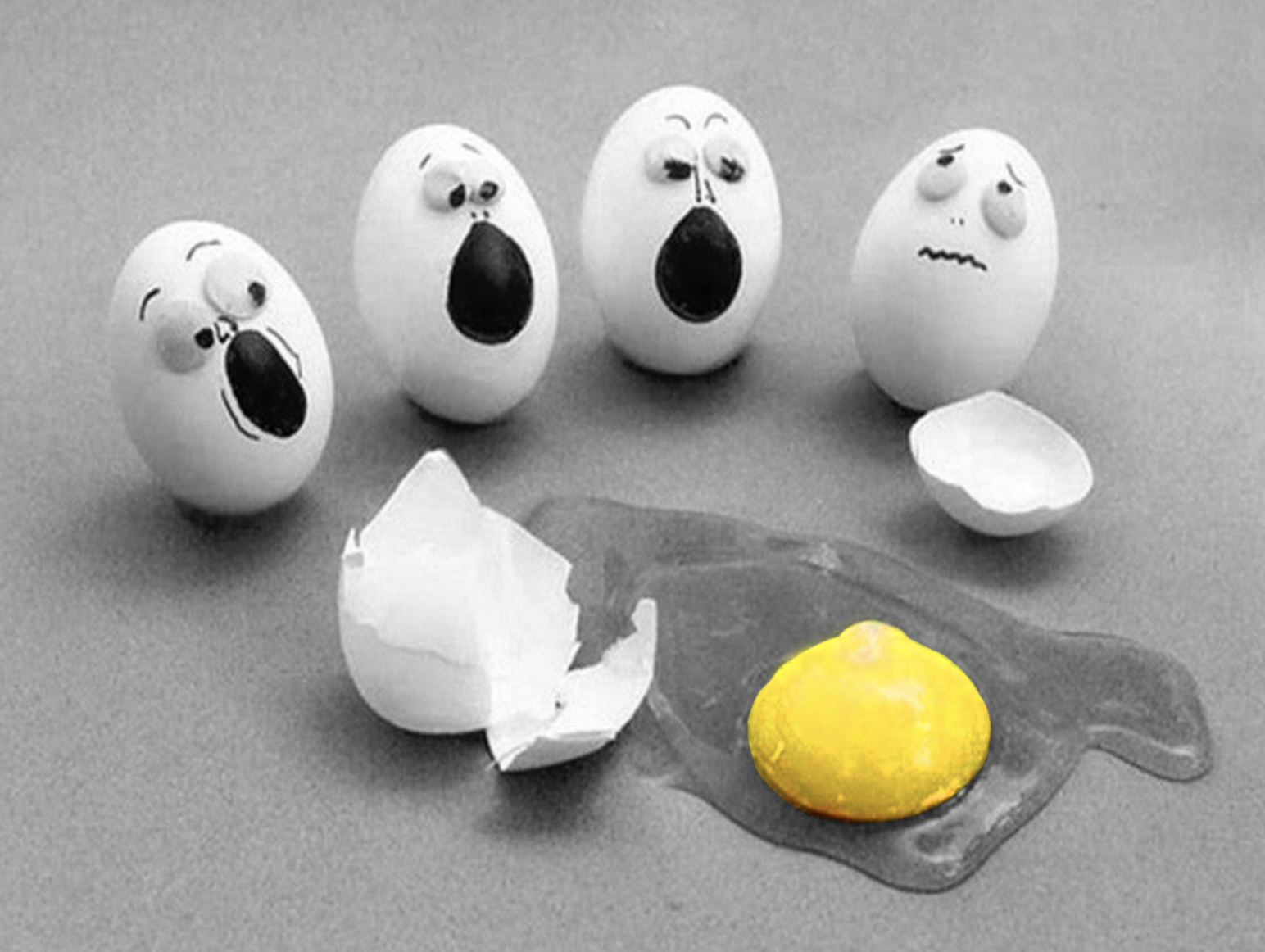 Photo of eggs with faces of shock and surprise drawn on them. THey are "looking" at a cracked egg with the yolk on the ground. It's a silly joke that they are looking at their "cracked open" friend.